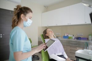 A female dentist using a tablet while attending to a patient in a modern dental clinic.